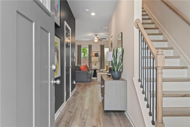 hallway with stairs, light wood-type flooring, baseboards, and recessed lighting