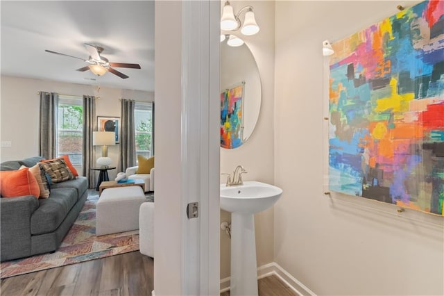 bathroom featuring wood finished floors, a ceiling fan, baseboards, and a sink