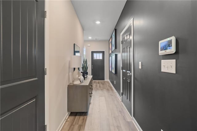 hall featuring light wood-type flooring, baseboards, and recessed lighting
