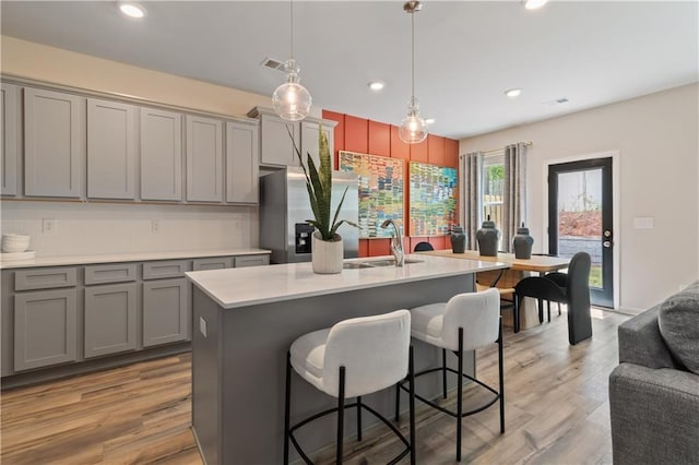 kitchen with gray cabinetry, a sink, a kitchen breakfast bar, and recessed lighting