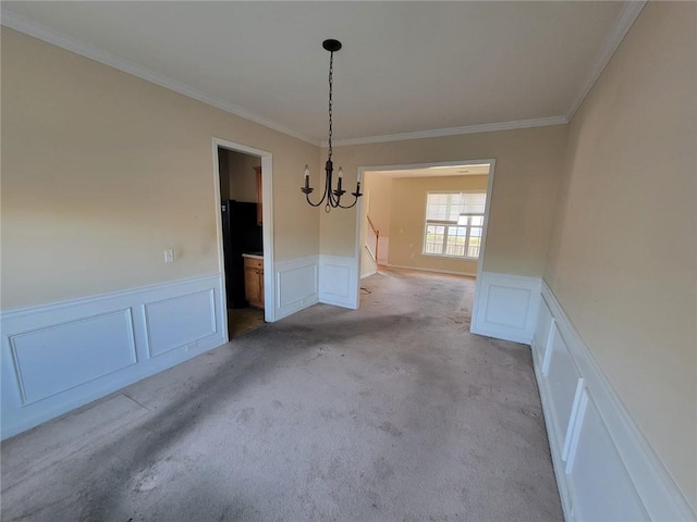 unfurnished dining area with a wainscoted wall, a decorative wall, and a notable chandelier