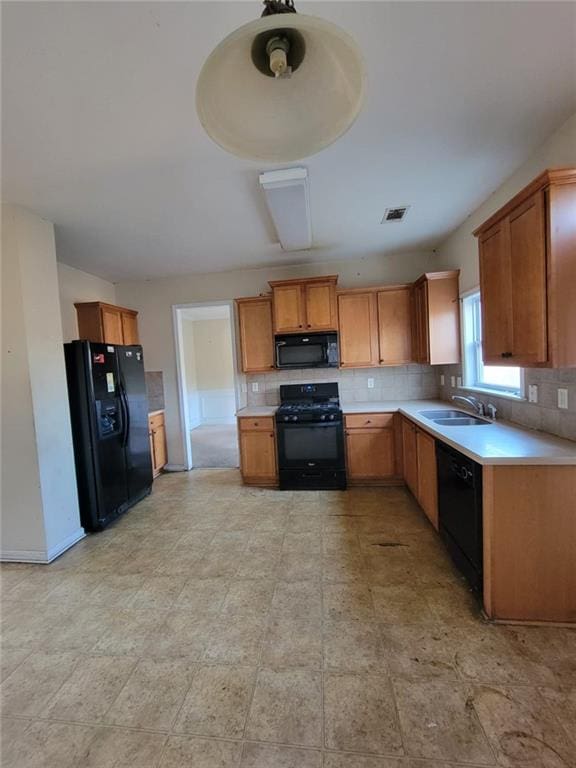 kitchen with light countertops, decorative backsplash, brown cabinetry, a sink, and black appliances