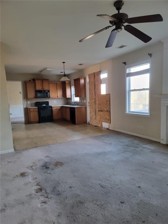 kitchen featuring open floor plan, hanging light fixtures, light countertops, black appliances, and brown cabinetry