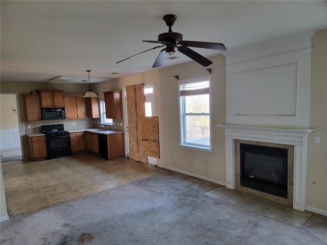 kitchen featuring light colored carpet, light countertops, hanging light fixtures, brown cabinetry, and black appliances