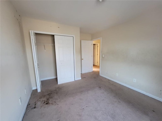 unfurnished bedroom featuring light carpet, a closet, and baseboards