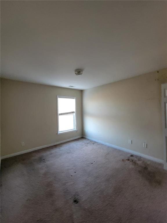 empty room featuring baseboards and carpet flooring