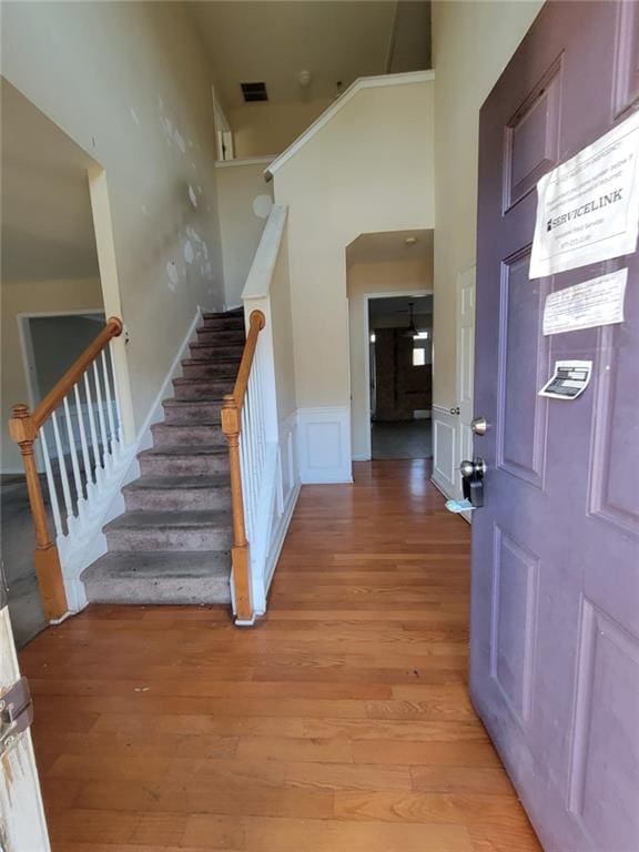 foyer featuring a wainscoted wall, light wood finished floors, visible vents, a decorative wall, and stairs