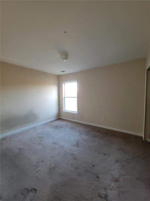 unfurnished room featuring carpet floors and baseboards