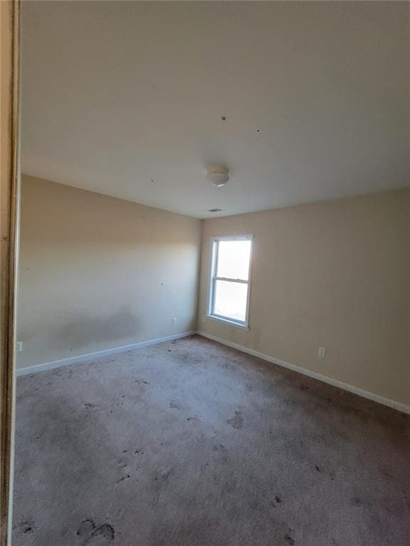 unfurnished room featuring carpet and baseboards