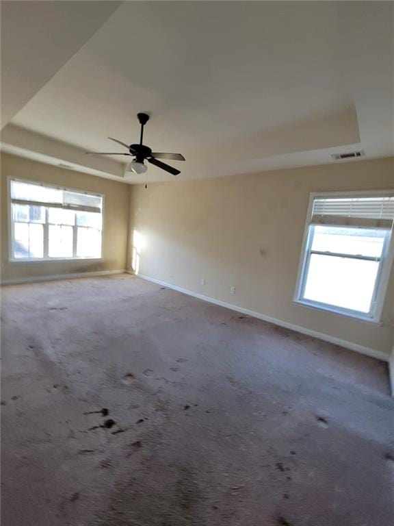 spare room featuring plenty of natural light, carpet, a raised ceiling, and visible vents