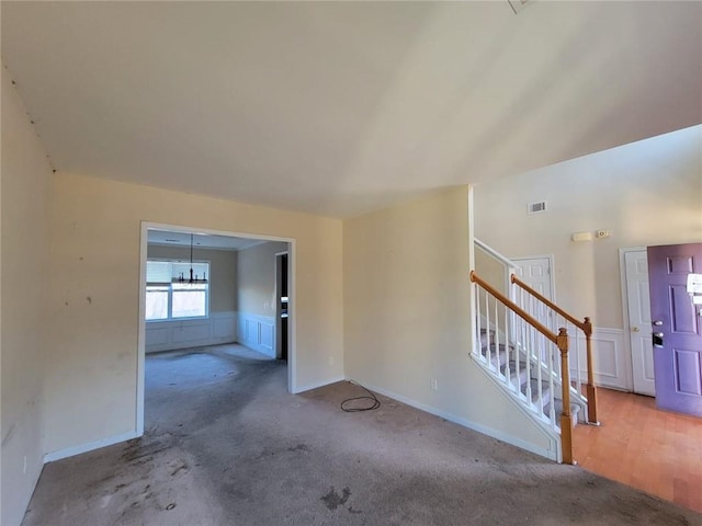 spare room with visible vents, stairway, and a decorative wall