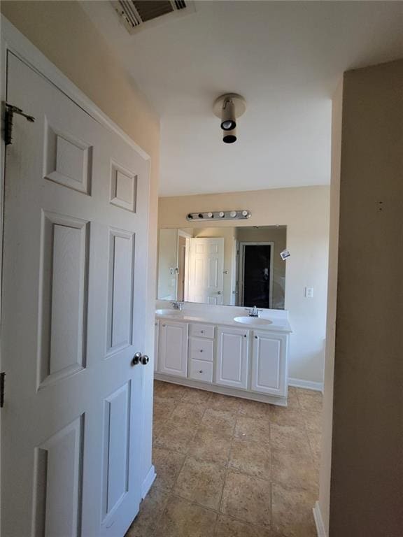 full bathroom with double vanity, a sink, visible vents, and baseboards