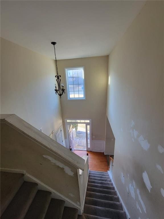 staircase with baseboards, a high ceiling, and a chandelier