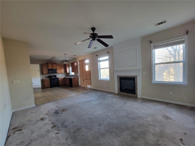 unfurnished living room with light colored carpet, visible vents, a glass covered fireplace, and baseboards