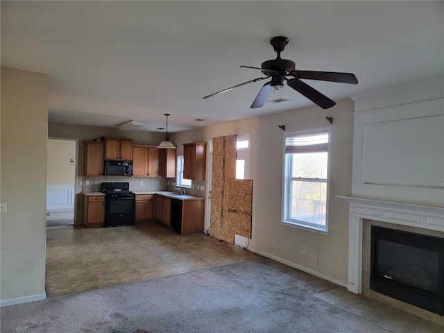 kitchen featuring light carpet, light countertops, black appliances, brown cabinetry, and decorative light fixtures