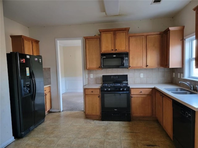 kitchen with a sink, light countertops, brown cabinets, decorative backsplash, and black appliances