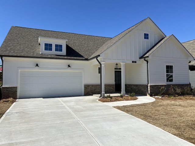 view of front of property featuring driveway, roof with shingles, an attached garage, board and batten siding, and brick siding