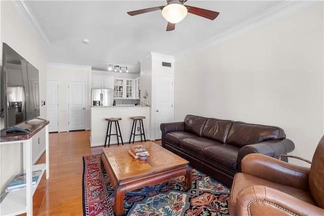 living room with rail lighting, light hardwood / wood-style flooring, ceiling fan, and crown molding