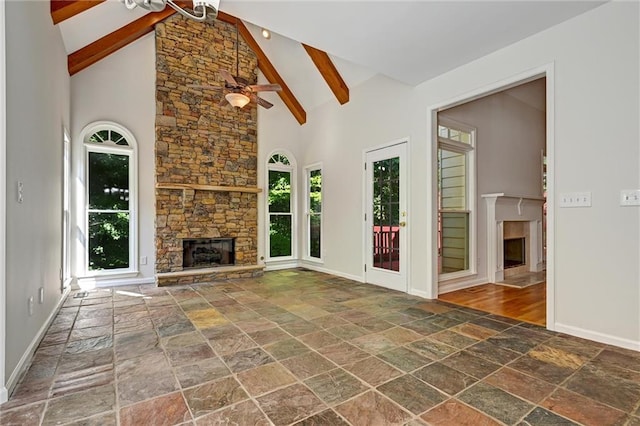 unfurnished living room with ceiling fan, high vaulted ceiling, beam ceiling, and a fireplace