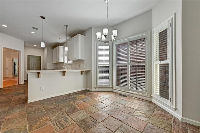 kitchen featuring white cabinets, decorative light fixtures, a chandelier, kitchen peninsula, and a breakfast bar