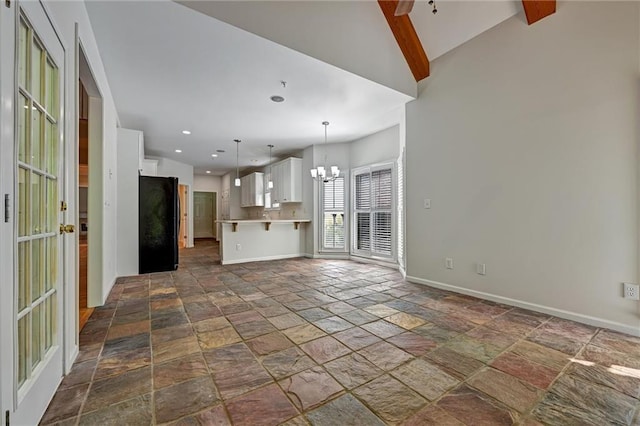 unfurnished living room with an inviting chandelier and lofted ceiling with beams