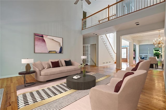 living room featuring light hardwood / wood-style flooring, a towering ceiling, and ceiling fan with notable chandelier