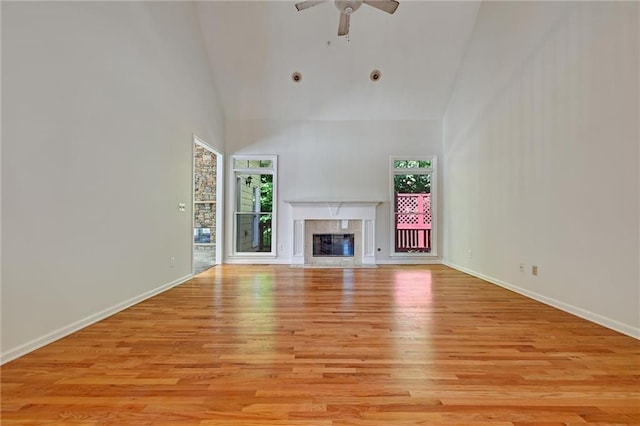 unfurnished living room featuring light hardwood / wood-style flooring, ceiling fan, high vaulted ceiling, and a fireplace