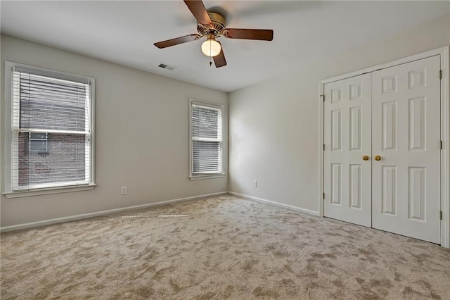 unfurnished bedroom featuring light colored carpet, ceiling fan, and a closet