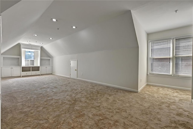 additional living space with light carpet and vaulted ceiling