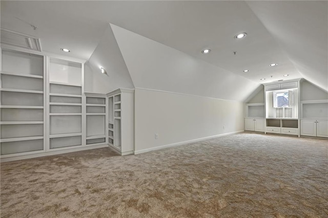 bonus room with built in shelves, carpet, and vaulted ceiling