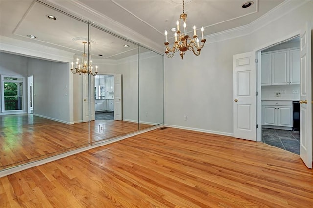 unfurnished room with crown molding, hardwood / wood-style floors, and a notable chandelier