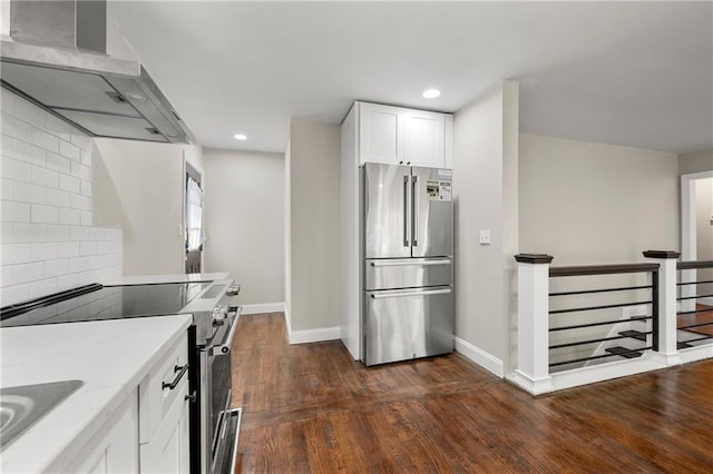 kitchen with wall chimney range hood, appliances with stainless steel finishes, light stone countertops, white cabinets, and decorative backsplash