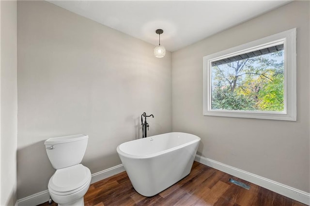 bathroom with a bath, wood-type flooring, and toilet