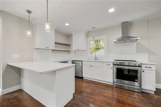 kitchen with white cabinets, stainless steel appliances, decorative light fixtures, and wall chimney range hood