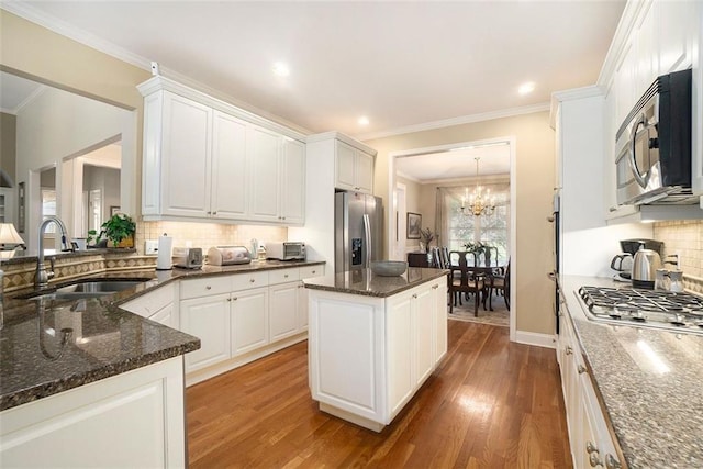 4653 Glory Maple Trce, Powder Springs, GA 30127 - kitchen featuring appliances with stainless steel finishes, wood finished floors, white cabinetry, a kitchen island, and ornamental molding