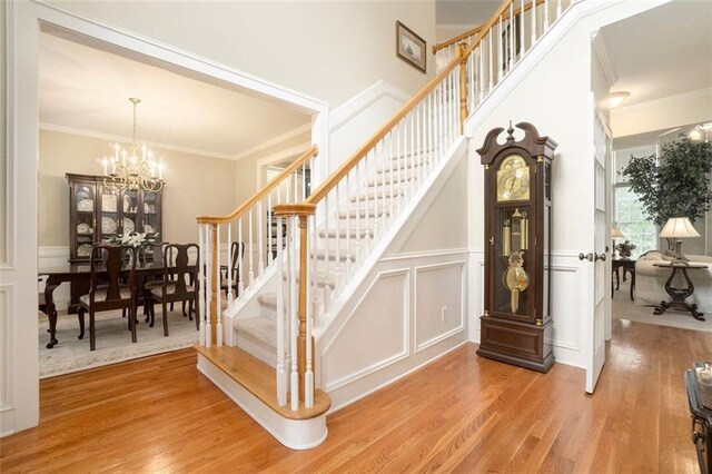 4653 Glory Maple Trce, Powder Springs, GA 30127 - stairs featuring a chandelier, crown molding, wood finished floors, a decorative wall, and wainscoting