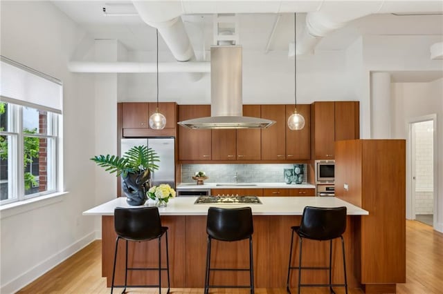 1058 Piedmont Ave Unit 103, Atlanta, GA 30309 - kitchen featuring stainless steel appliances, island range hood, brown cabinets, light countertops, and baseboards