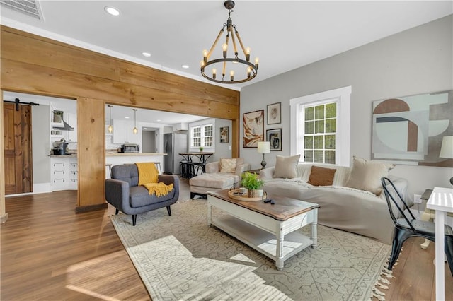 living room with a notable chandelier, a barn door, and light hardwood / wood-style floors