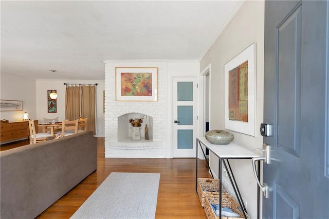 interior space with a brick fireplace, wood finished floors, and crown molding