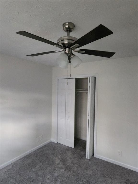 unfurnished bedroom with ceiling fan, dark carpet, a textured ceiling, and a closet