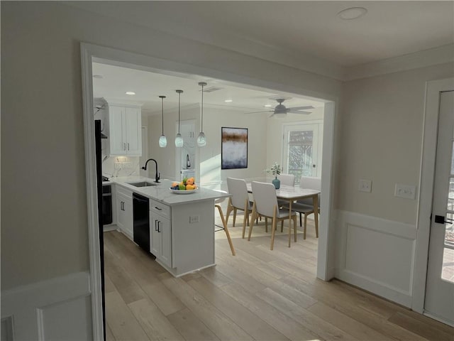 kitchen with sink, white cabinets, dishwasher, and hanging light fixtures