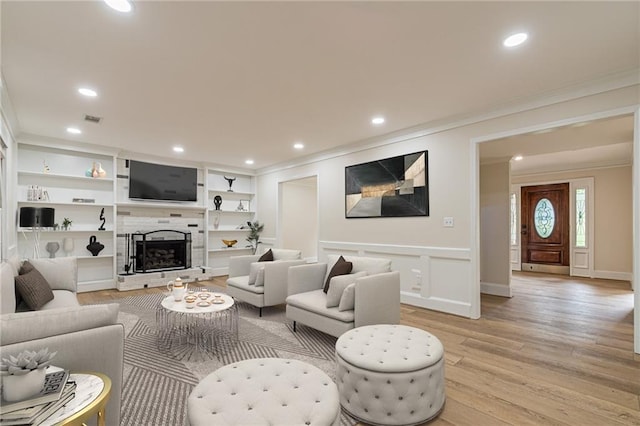 living room featuring built in features, crown molding, and light hardwood / wood-style flooring