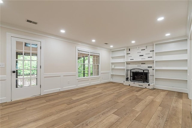 unfurnished living room featuring light hardwood / wood-style floors, crown molding, and a fireplace