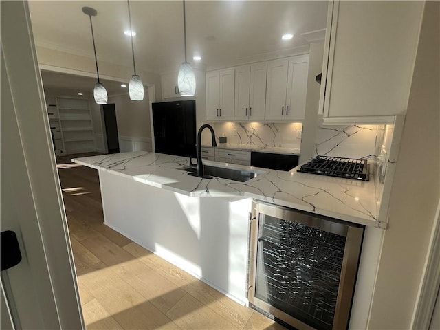 kitchen featuring black refrigerator, light stone countertops, sink, white cabinets, and wine cooler