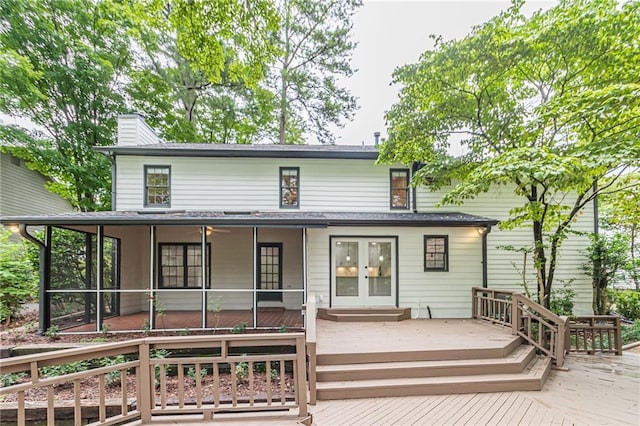 rear view of house featuring a sunroom, a wooden deck, and french doors