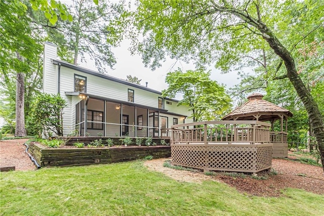 rear view of property featuring a lawn, a sunroom, and a gazebo