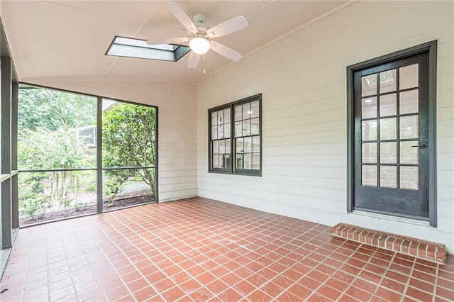 unfurnished sunroom featuring vaulted ceiling with skylight and ceiling fan