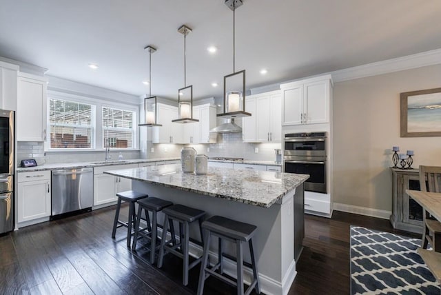 kitchen featuring hanging light fixtures, a kitchen island, white cabinets, and appliances with stainless steel finishes