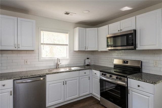 kitchen with dark stone countertops, sink, white cabinets, and appliances with stainless steel finishes