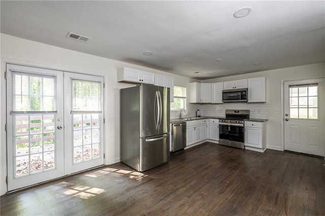 kitchen with dark wood-type flooring, french doors, white cabinetry, tasteful backsplash, and stainless steel appliances